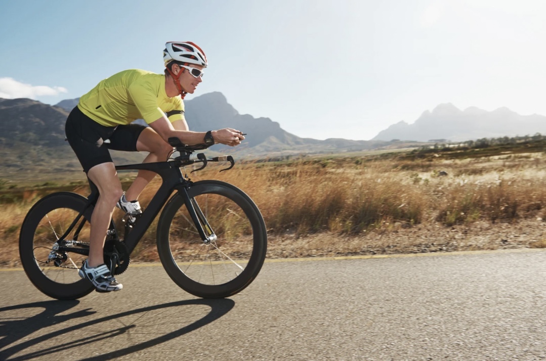 Ein Radfahrer beim Rennradfahren auf asphaltierter Strecke in der Natur